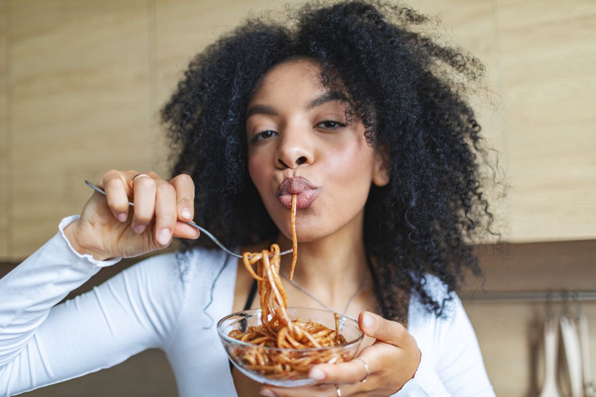 A woman eating a bowl of spaghetti