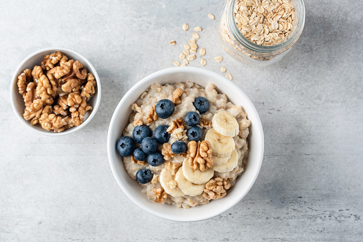 A bowl of porridge topped with banana, blueberries and walnuts