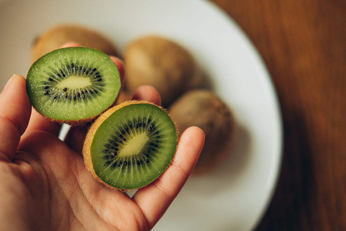A hand holds two halves of kiwi 