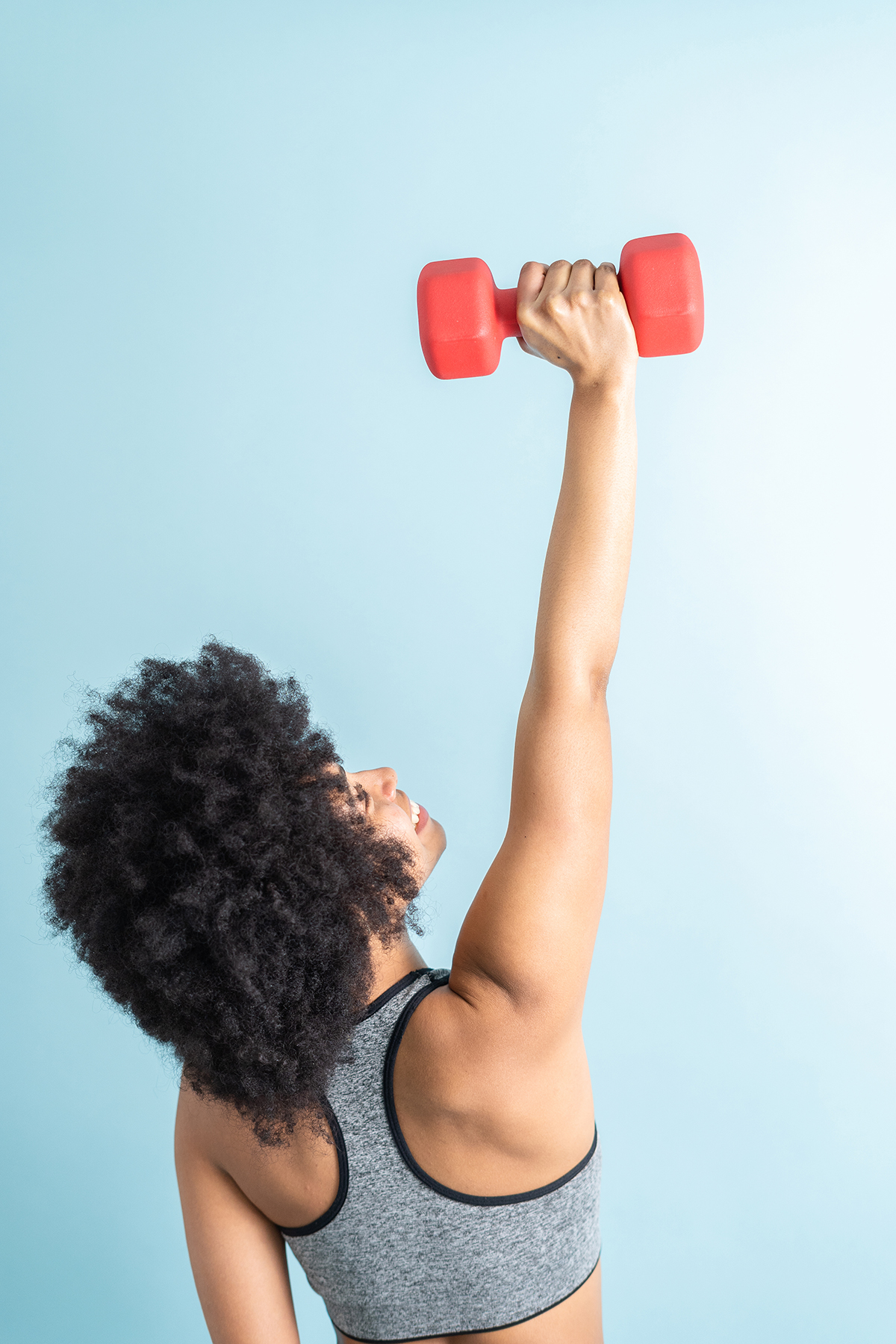 A woman lifting a dumbbell against a blue background