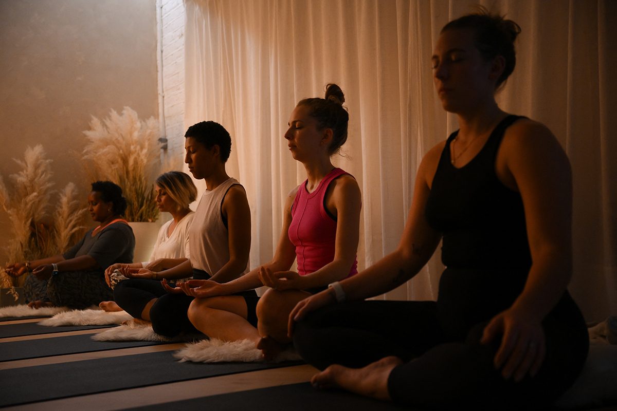 People meditating in a dimly lit yoga studio