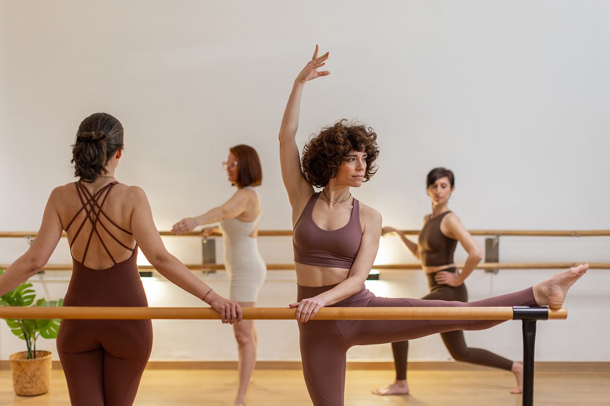 Women warming up next to a ballet barre in a modern studio