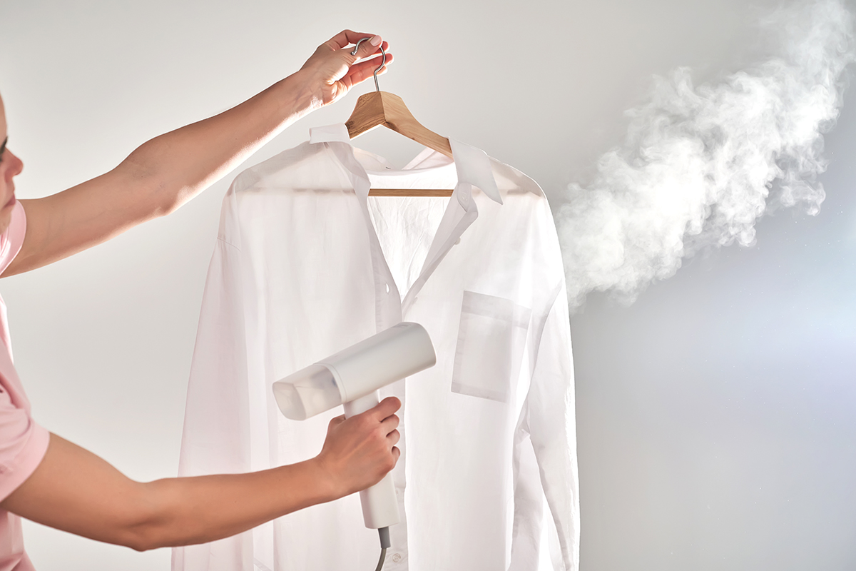 A woman steams a white shirt.