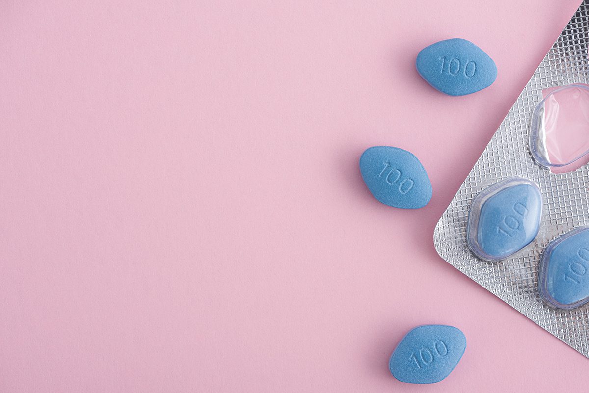 A pack of blue viagra pills on a pink background