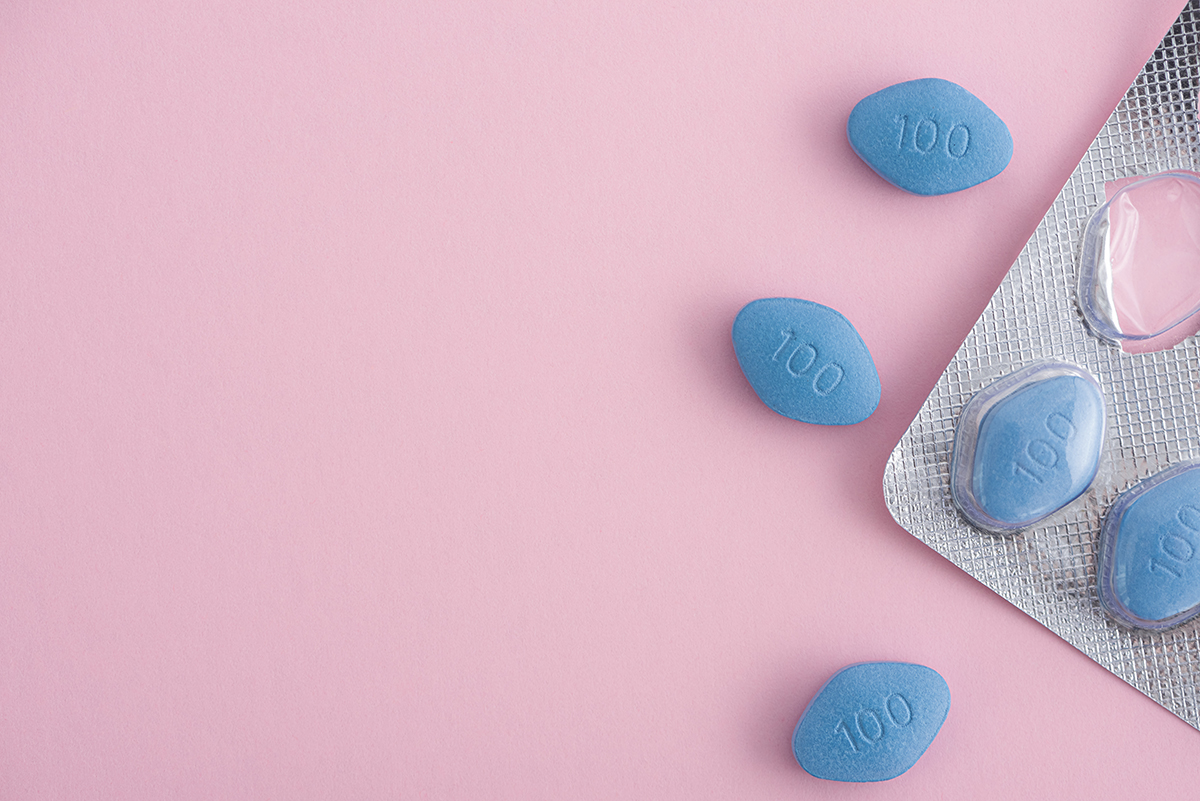 A pack of blue viagra pills on a pink background