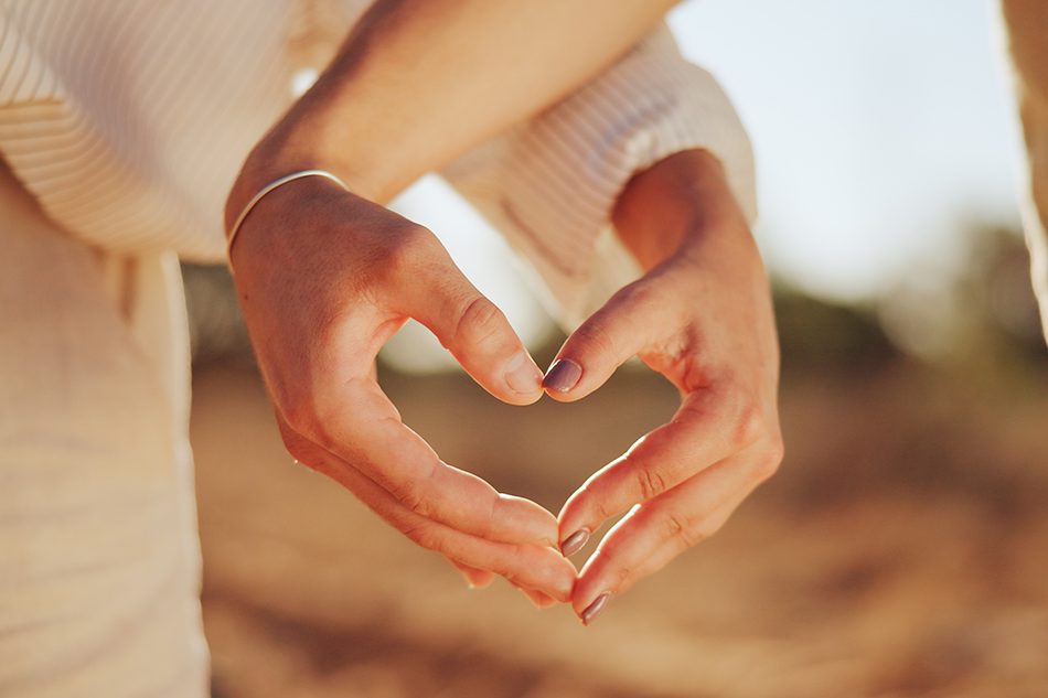 A couple making a heart shape with their hands