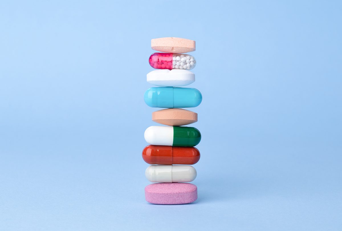 An assortment of colourful pills are stacked on top of each other against a blue background