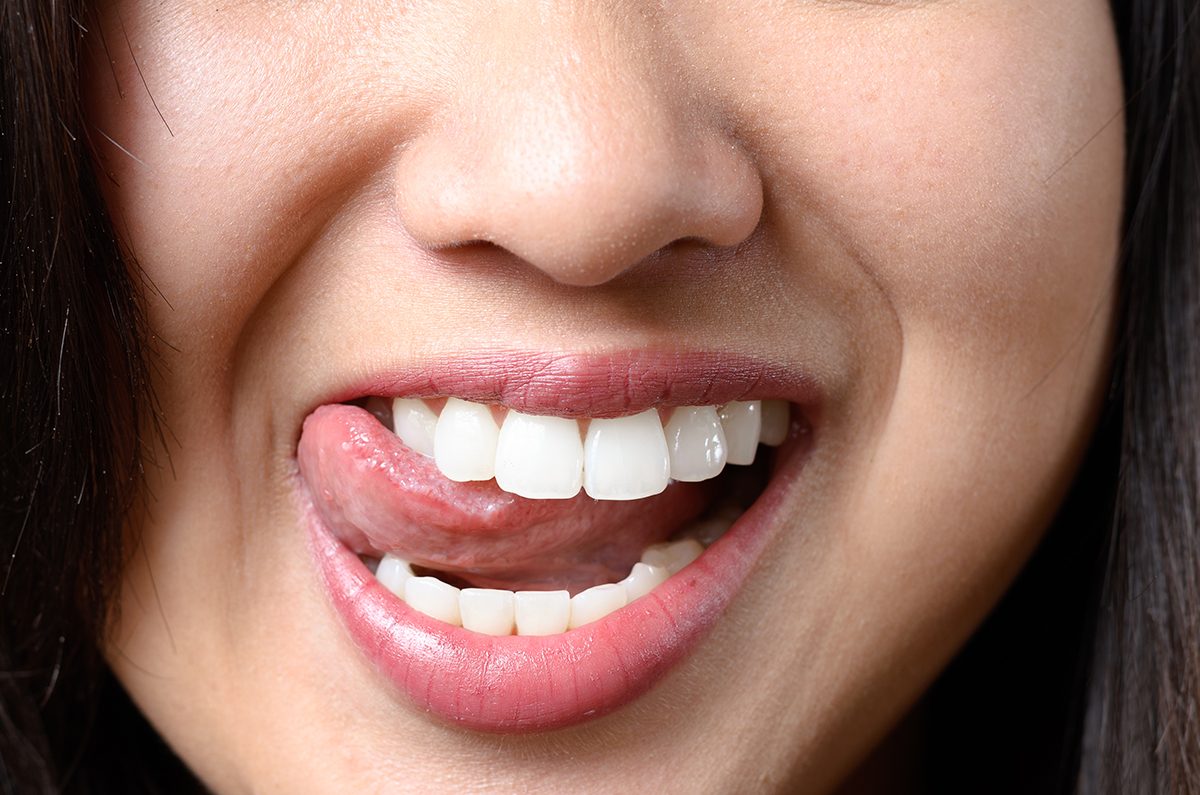 A close up of a woman licking her teeth.