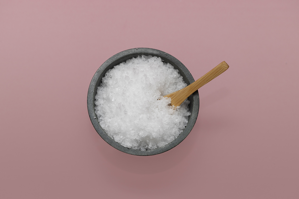 A bowl of sea salt on a pink background