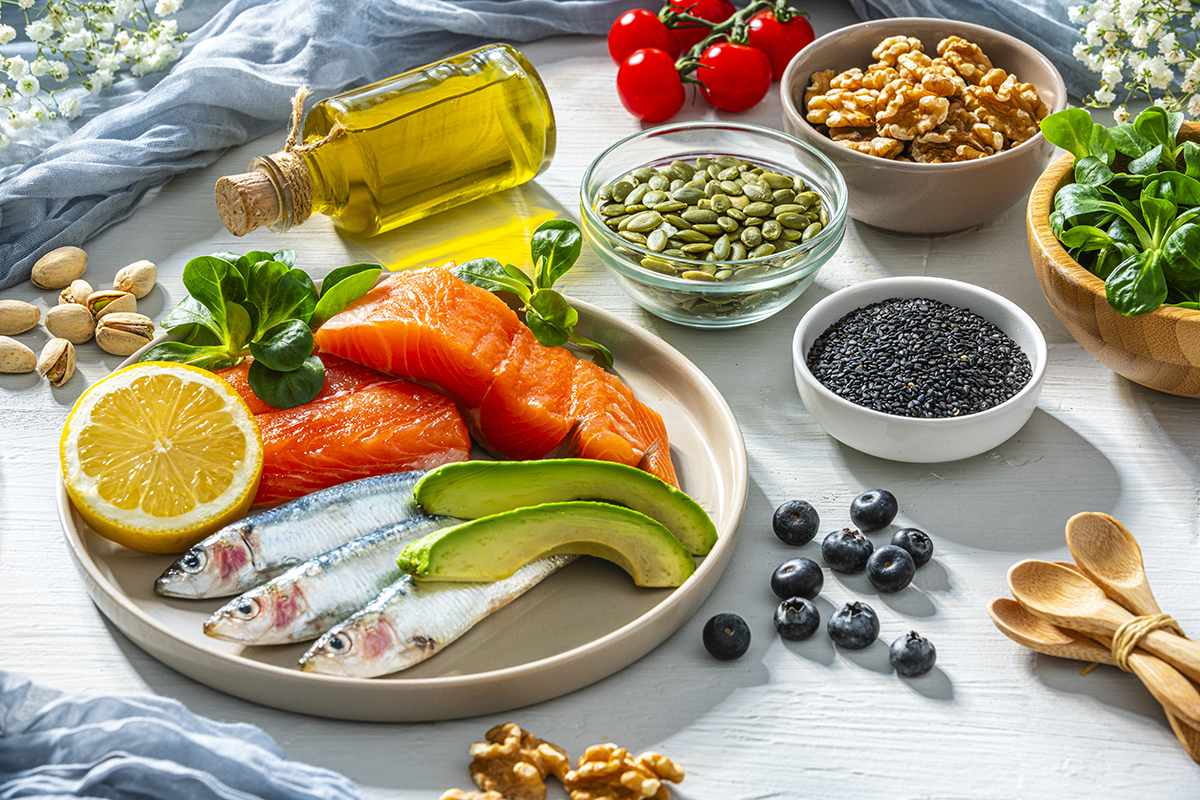 An assortment of healthy ingredients that are rich in Omega-3 and vitamin D, including fish, avocado, tomatoes, nuts and seeds