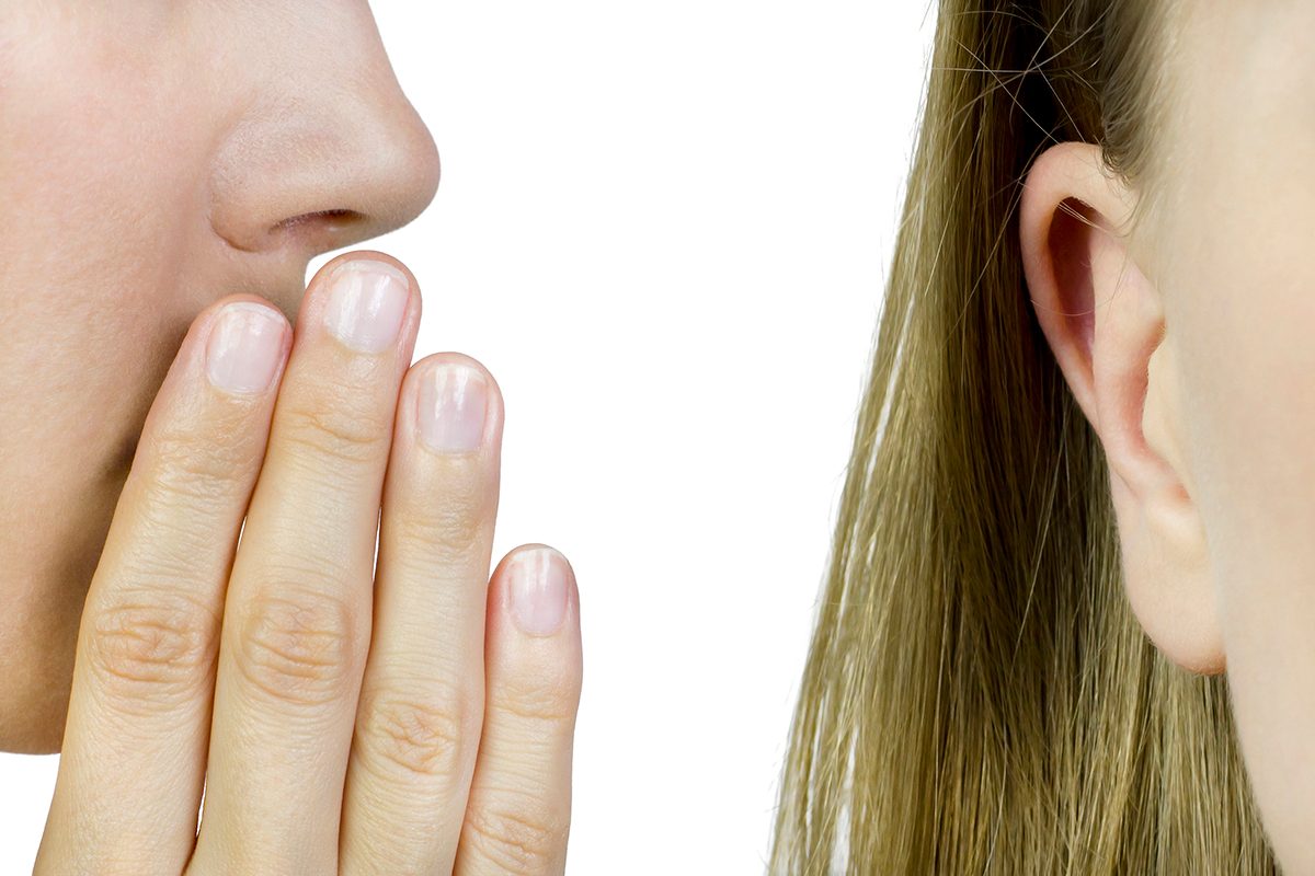 An extreme close-up of someone whispering in a woman's ear