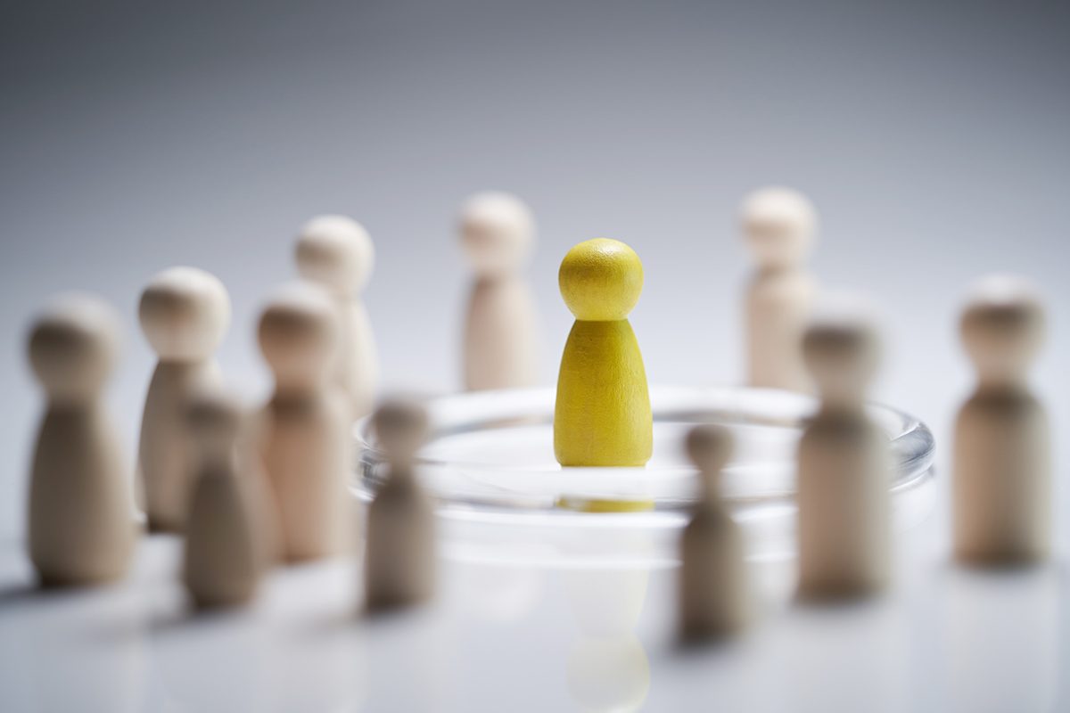 A yellow figure is positioned in the centre of a circle of wooden figurines