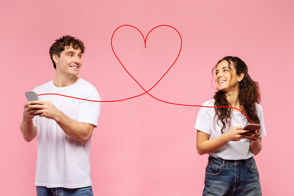 A couple holding mobile phones, connected with a piece of red string which forms a heart shape in the centre