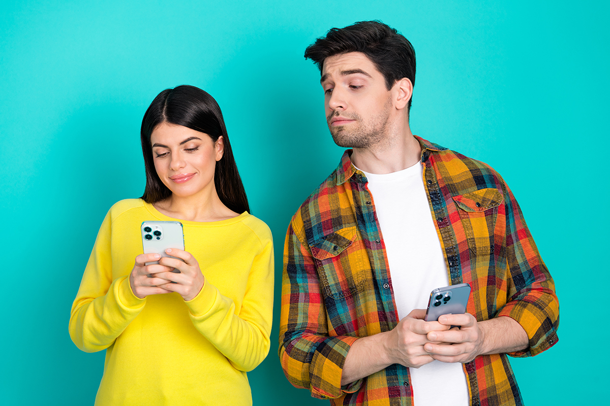 A man looking at a woman's phone as she types, smiling