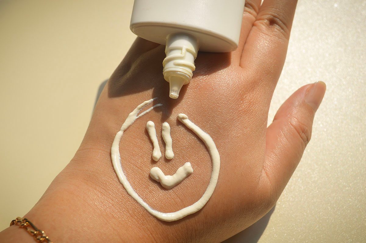 Suncream has been applied to a person's hand in the shape of a smiley face