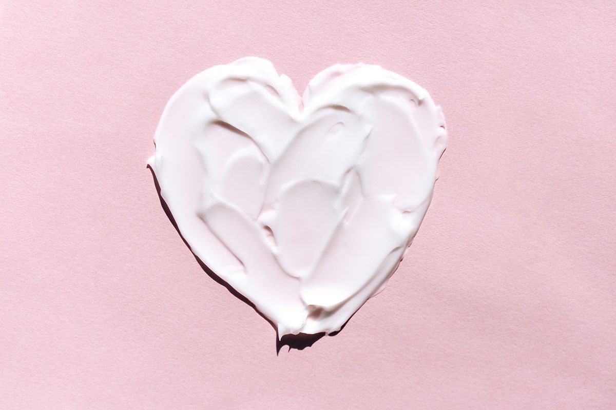 A heart shape has been drawn in a white cream on a pink background