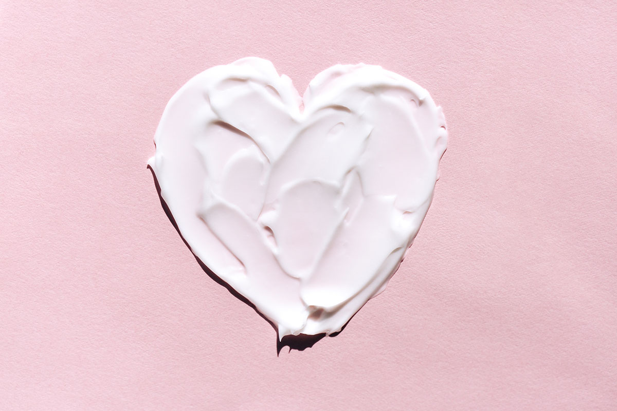 A heart shape has been drawn in a white cream on a pink background