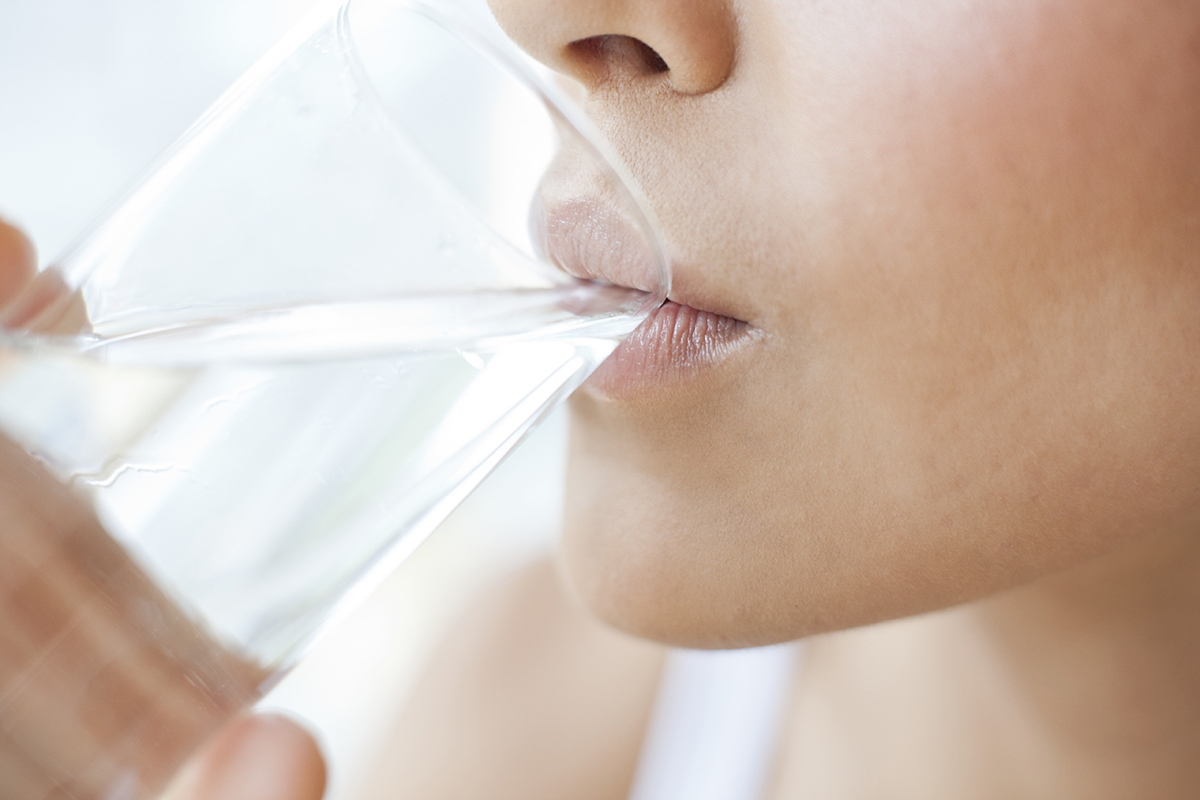 A close up of a woman drinking water from a glass.