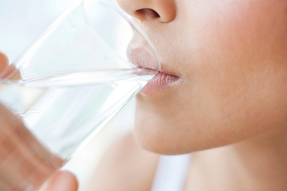 A close up of a woman drinking water from a glass.