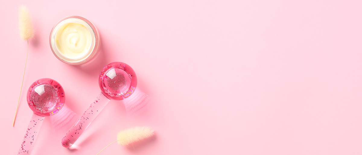 Ice globes and a pot of moisturiser on a pink background