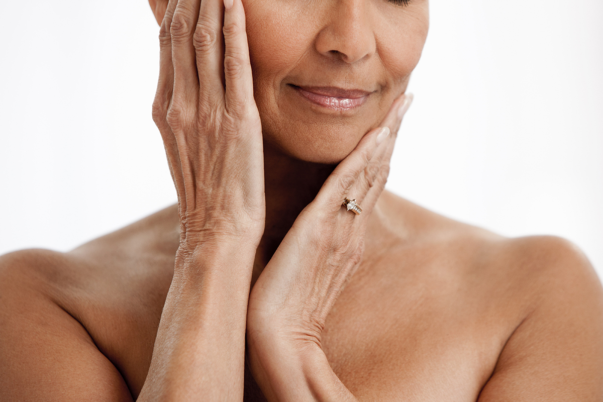 A cropped shot of a middle-aged woman with her hands on her face