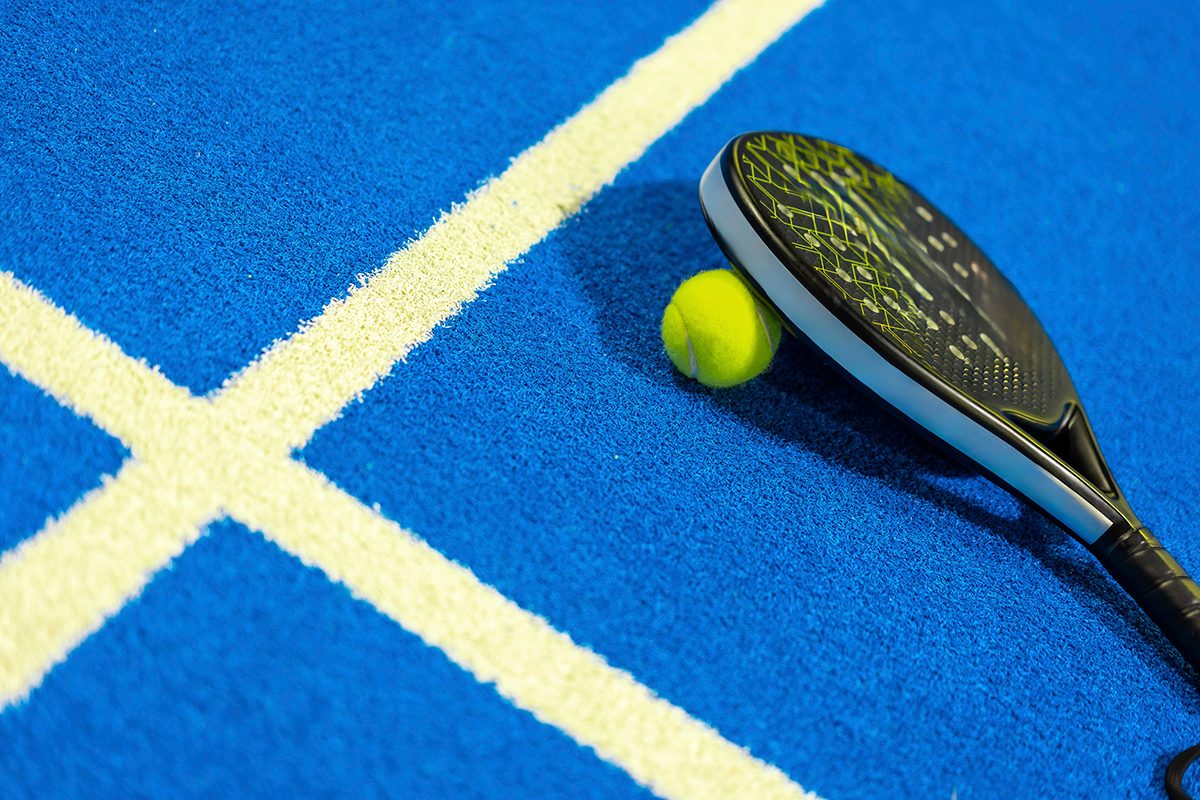 A padel racket and ball in an indoor padel court