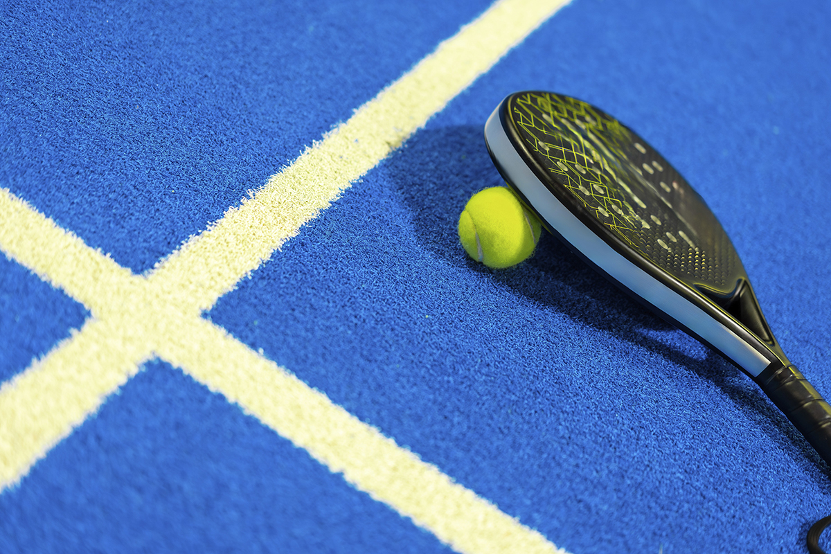 A padel racket and ball in an indoor padel court