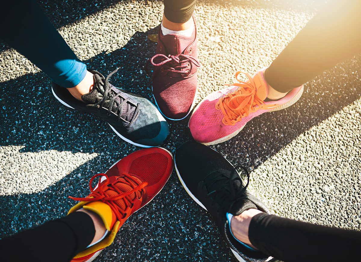 Five feet wearing running trainers are stood in a circle creating a star shape