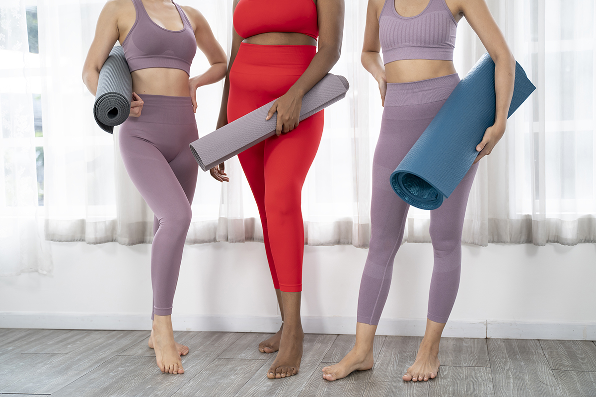 Three women holding yoga mats