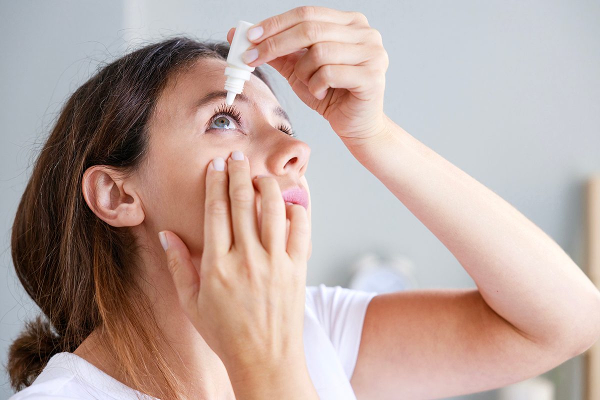 A woman administering eye drops at home