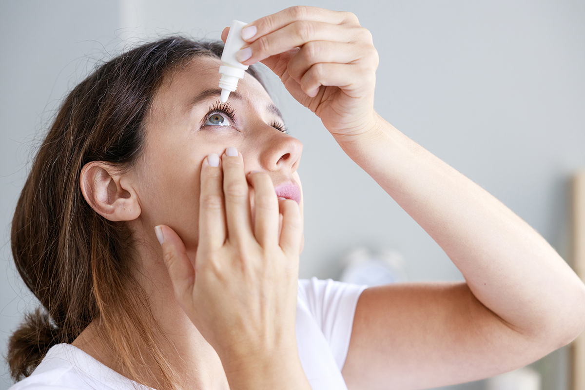 A woman administering eye drops at home