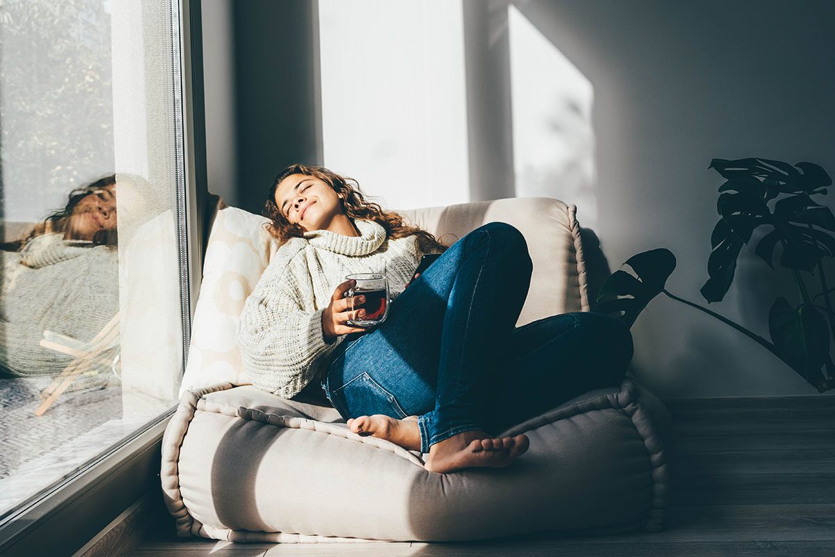 A woman relaxing on a sofa with a mug of tea