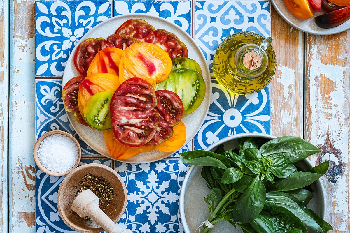 The ingredients for an heirloom tomato salad on Mediterranean tiles