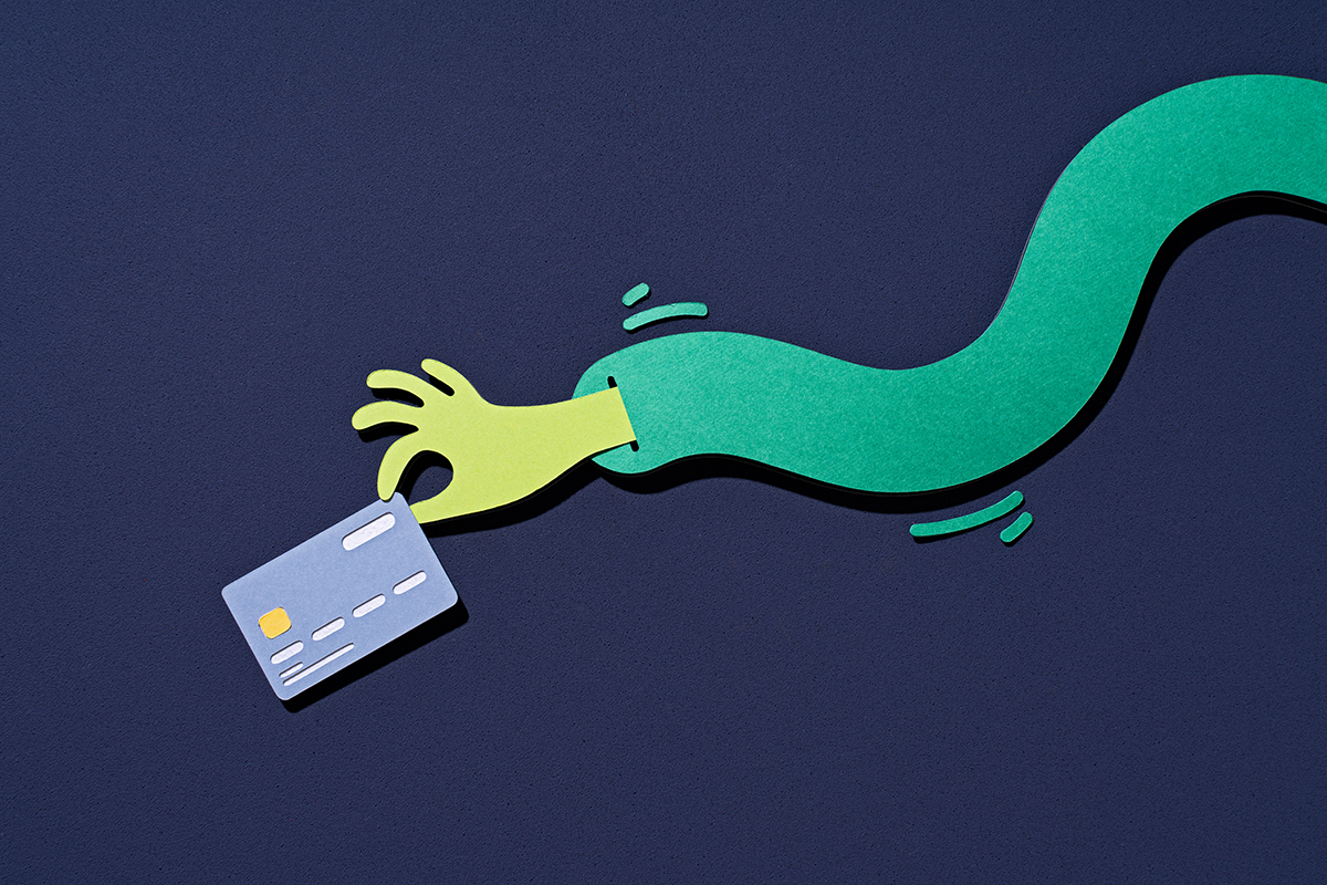 A paper craft hand picking up a credit card