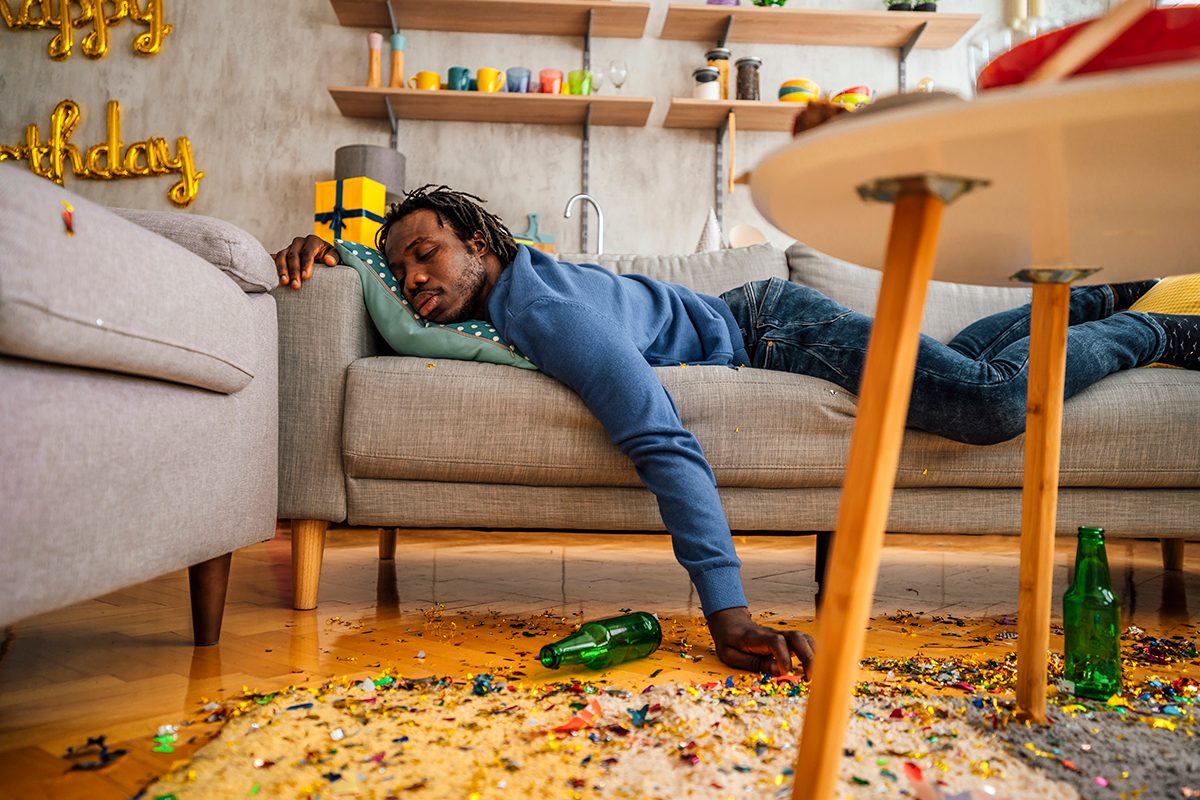 A drunk man is sleeping on a sofa after a party