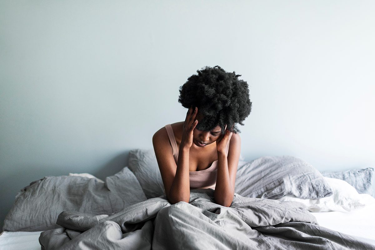 A woman sitting in bed with her head in her hands