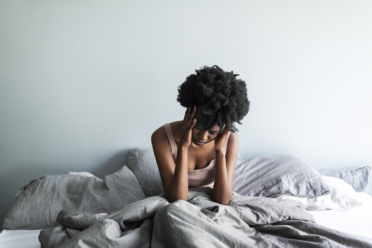 A woman sitting in bed with her head in her hands
