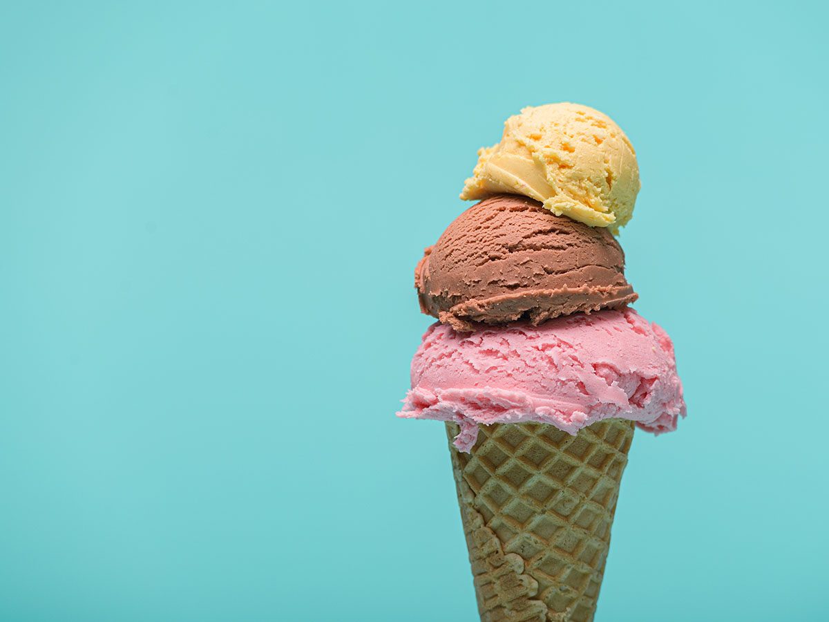 A triple scoop ice cream against a blue background