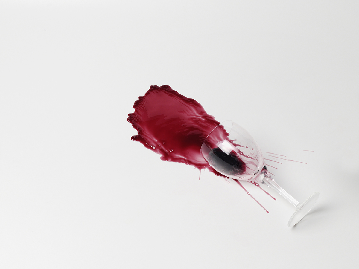 A glass of spilled red wine on a white background