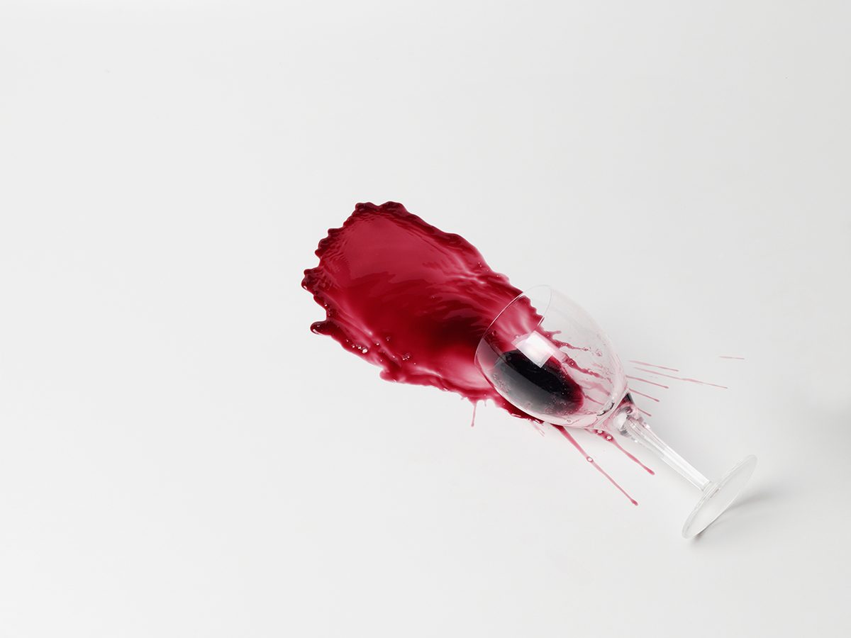 A glass of spilled red wine on a white background