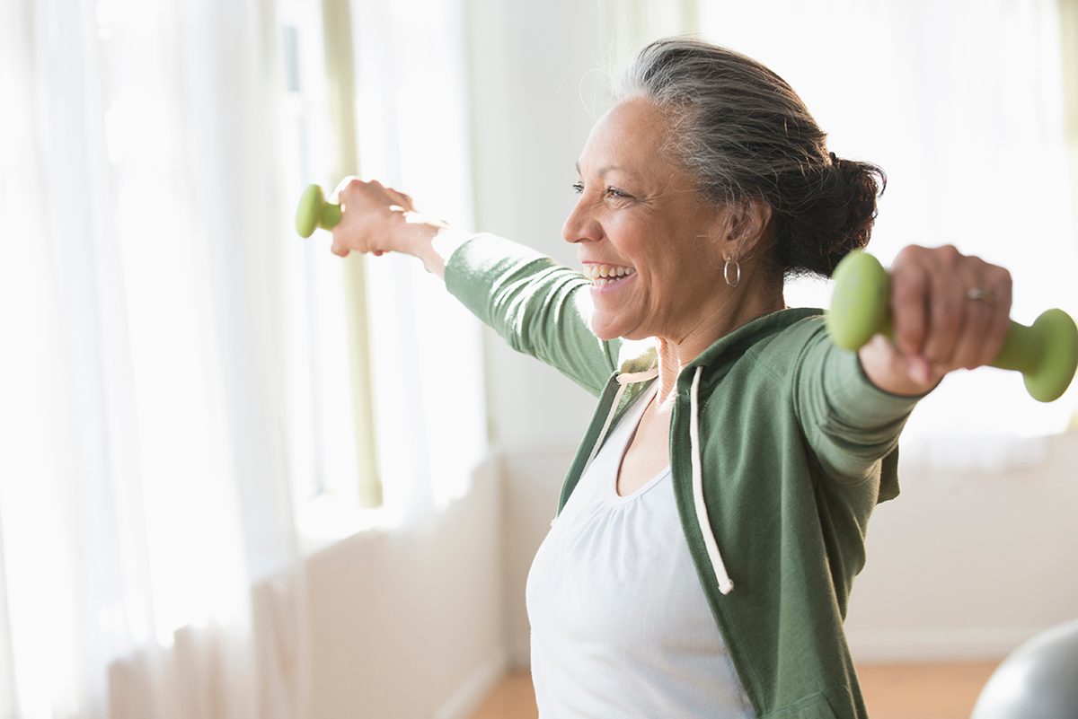 A woman is lifting hand weights in a living room