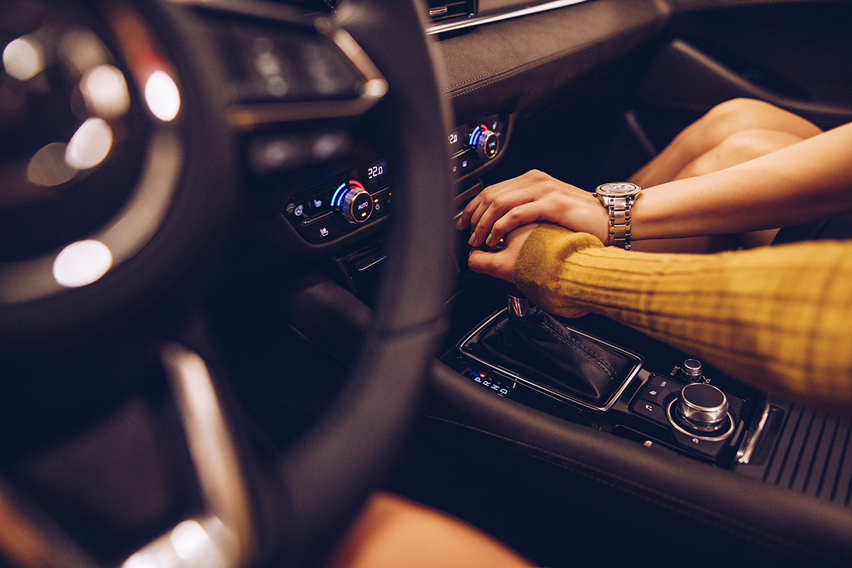 A couple holding hands over a gear stick