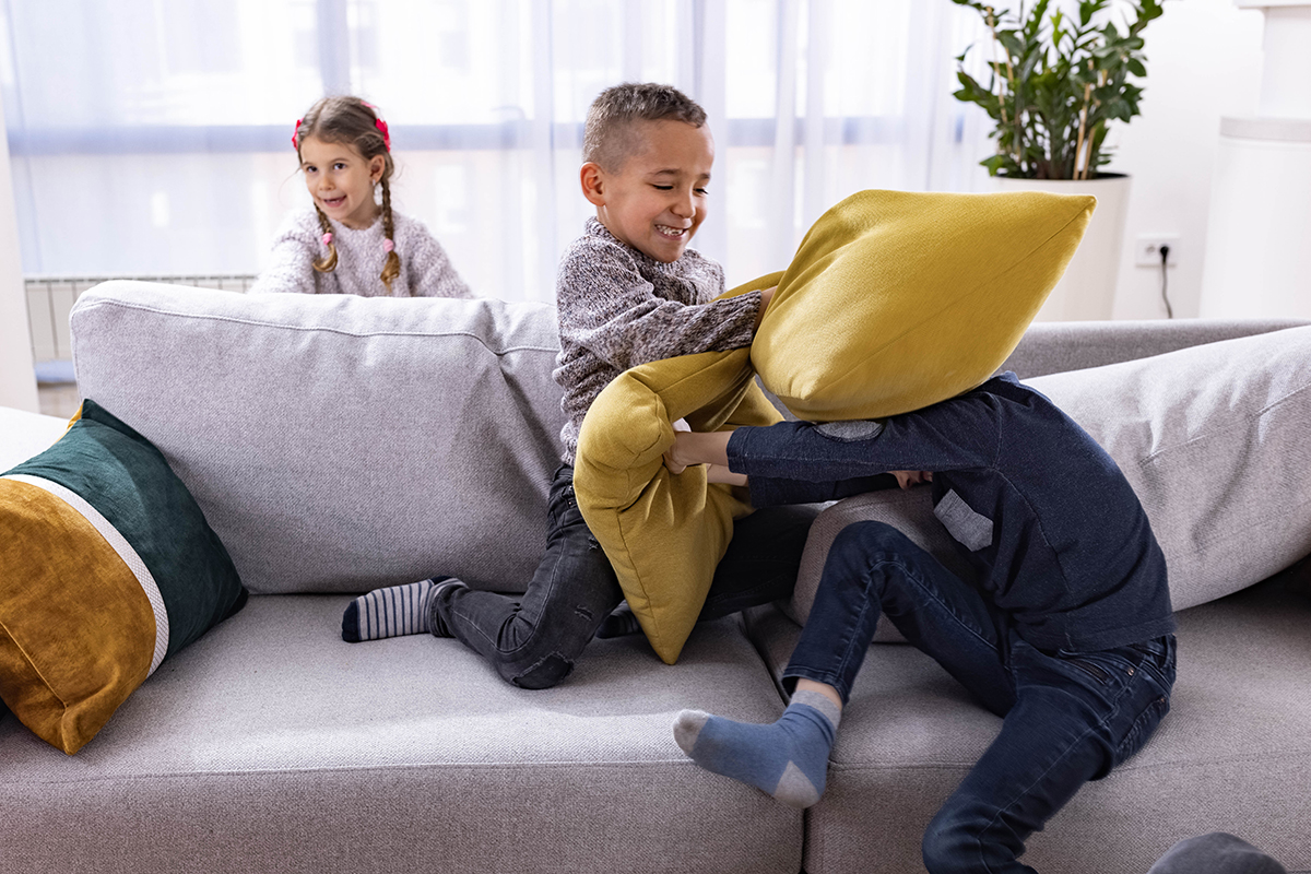Children having a pillow fight in a living room