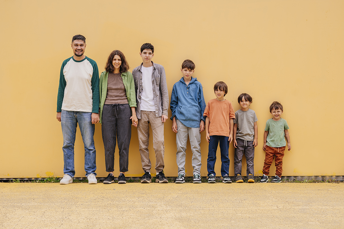 Two parents and five sons standing against a wall in height order