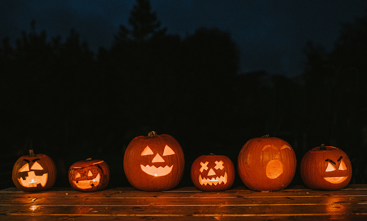 A line of carved pumpkins on a wooden floor