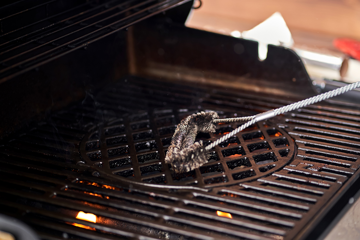 A close-up of someone cleaning a barbecue with a brush