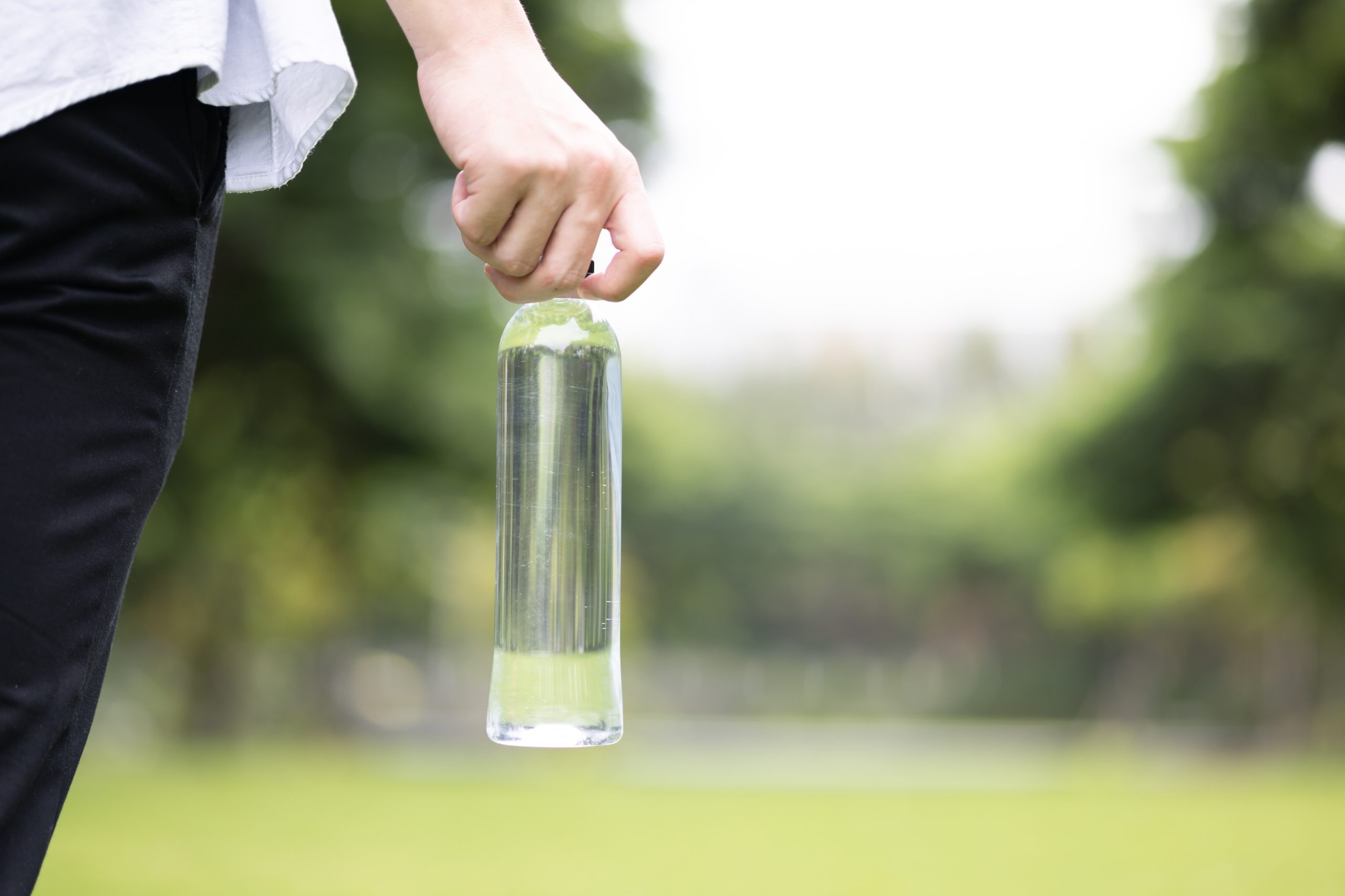 A person is holding a bottle of water in an outdoor setting