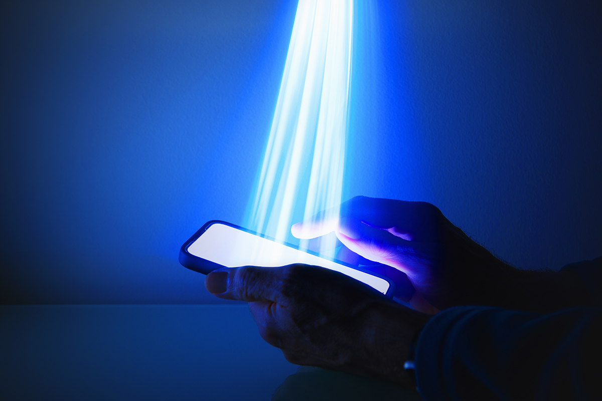 Hands holding a mobile phone with light being emitted from the screen