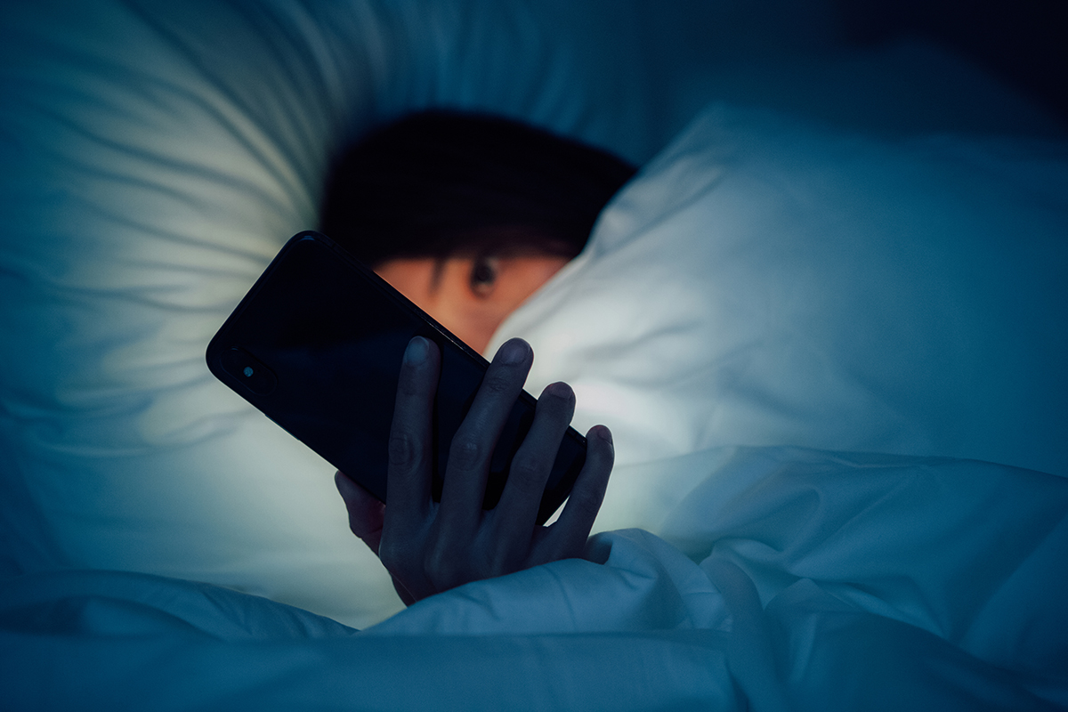 A woman looking at a mobile phone in bed