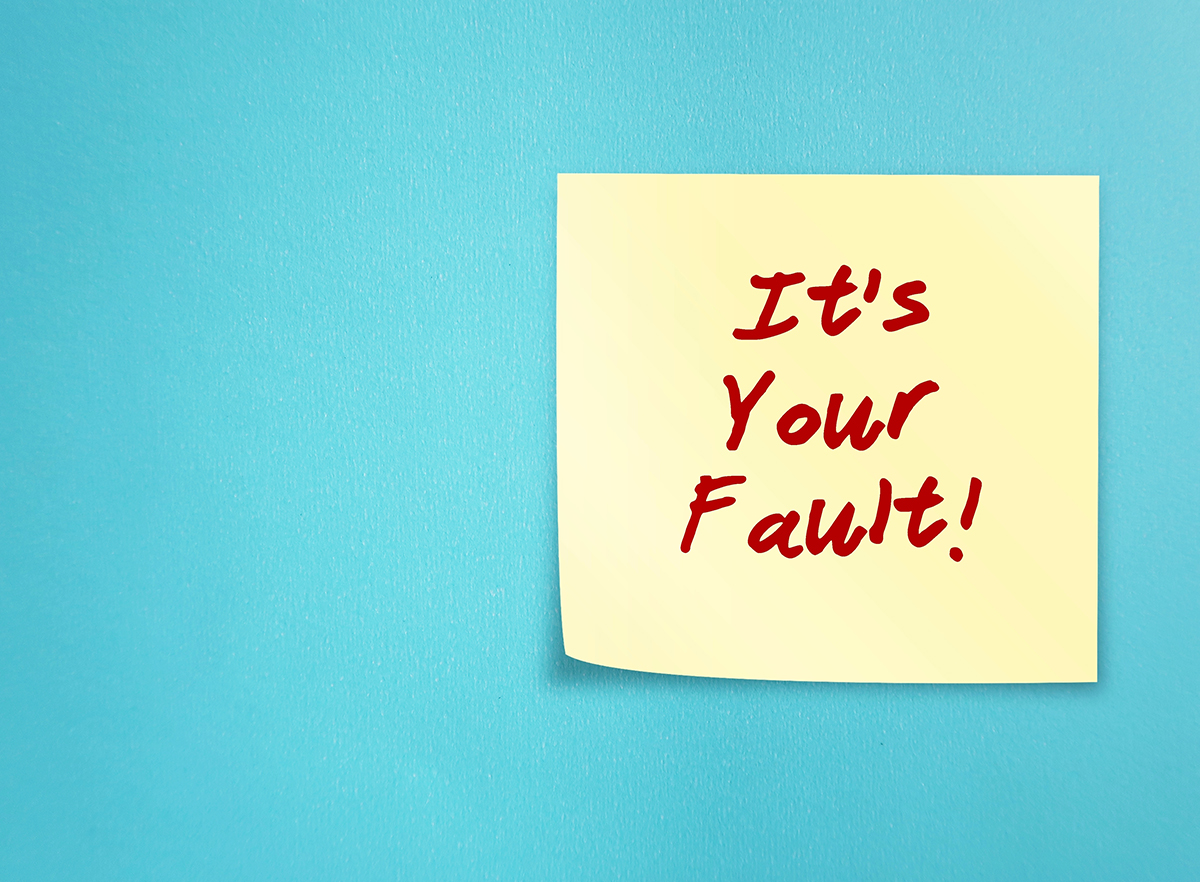A yellow sticky note that reads 'It's your fault!' on a blue background